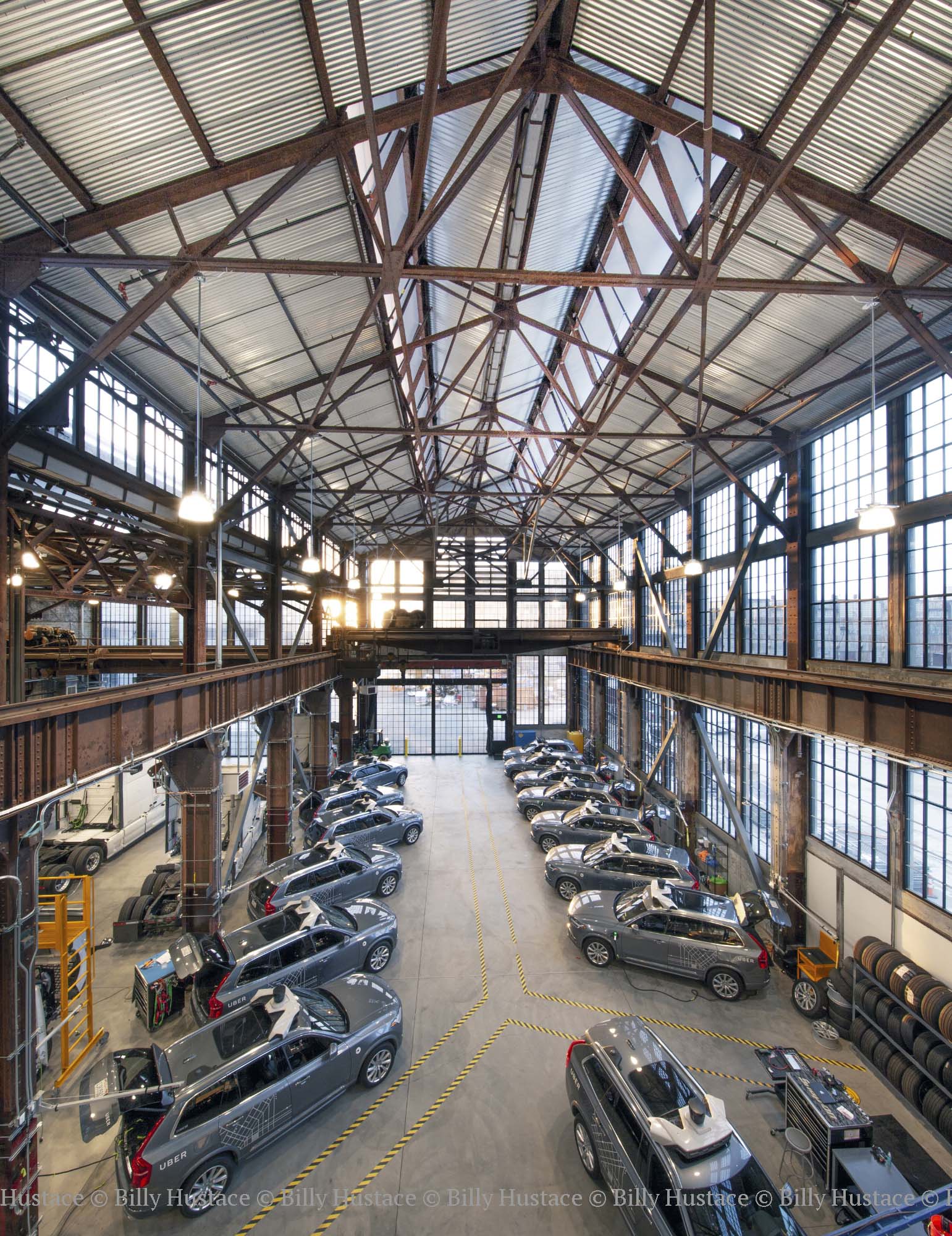 Interior view of a San Francisco building full of vehicles, hanging light fixtures, steel siding and large windows.