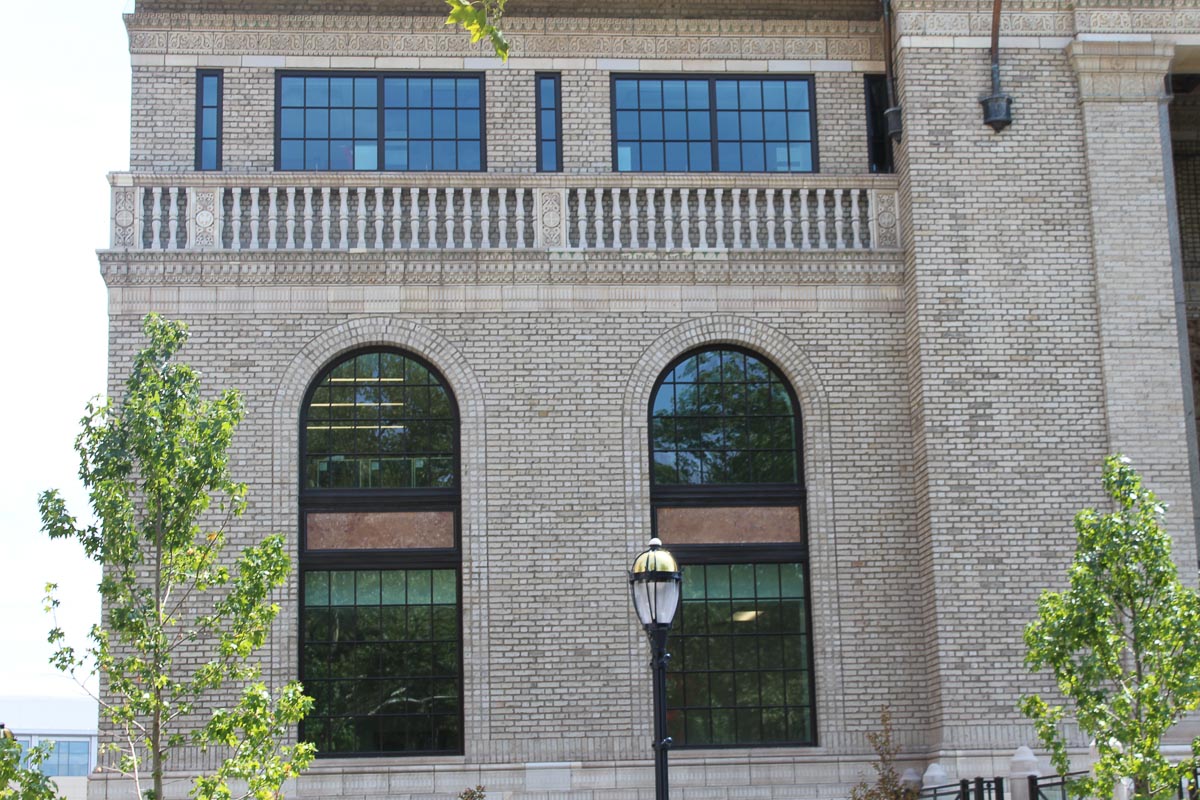 This brick commercial building has two large arched windows with other rectangular windows above them. 