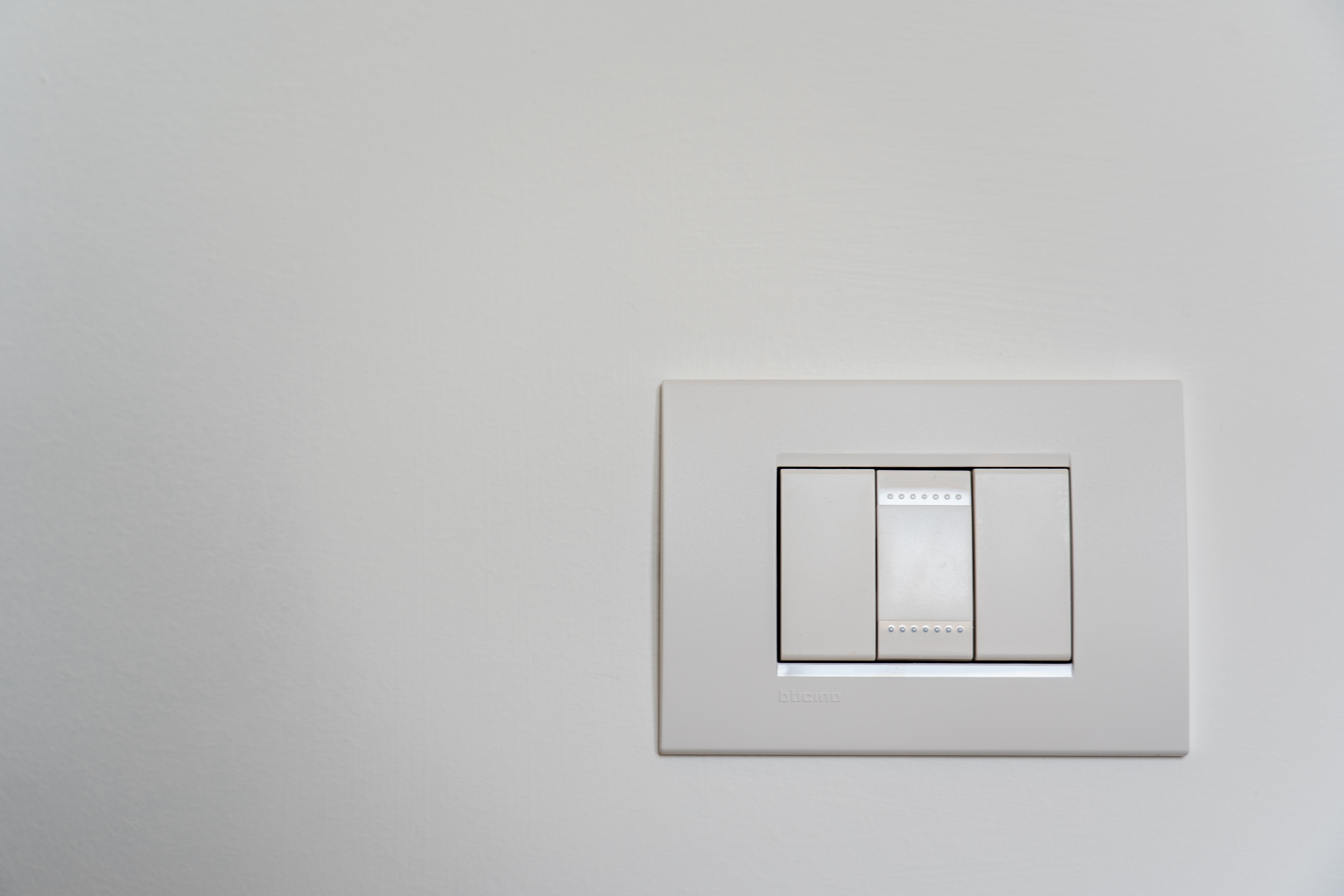 A light switch and sensor are mounted to a white wall.