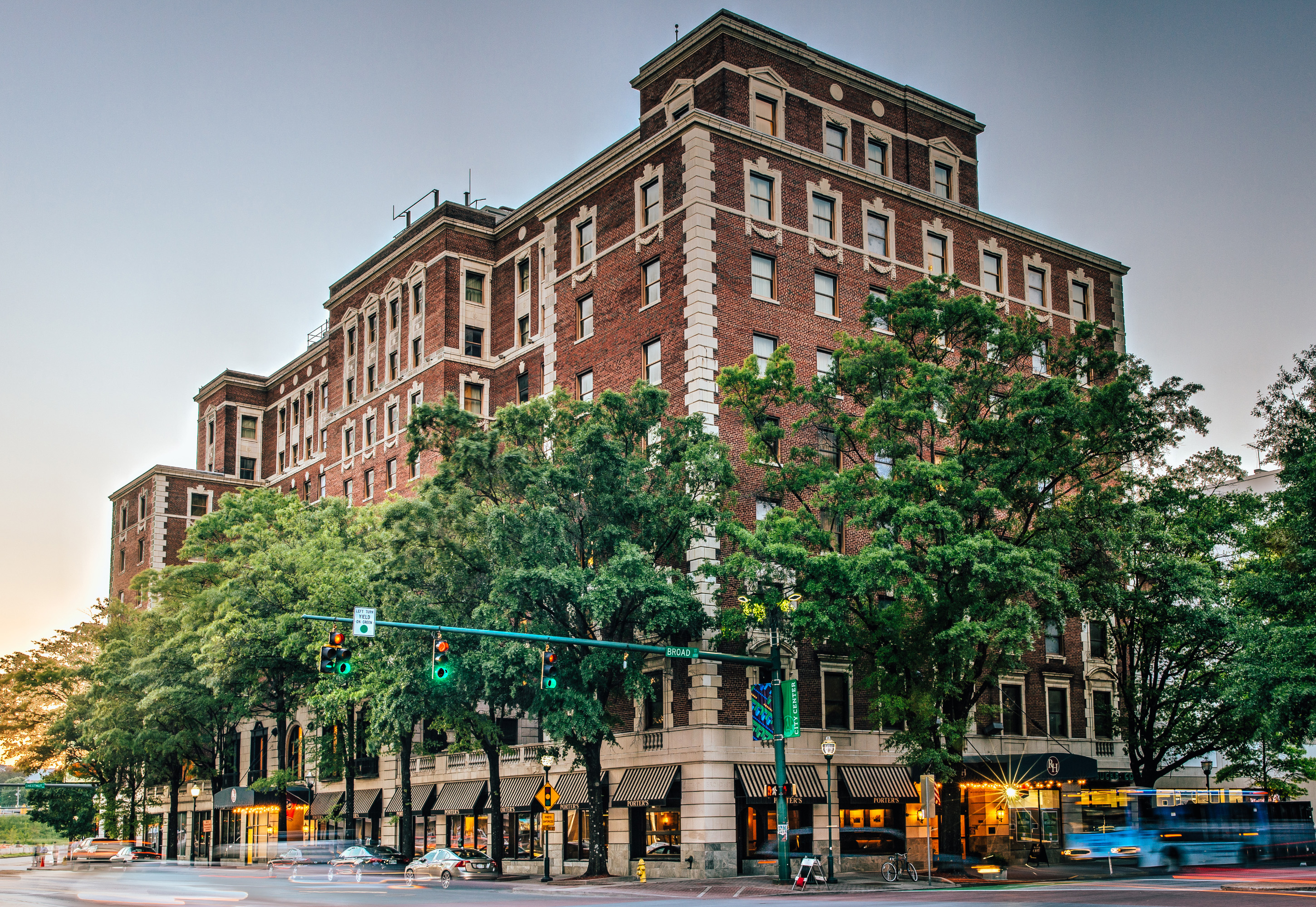 This commercial building has several large windows on each floor. There is a stoplight and cars moving on the street.