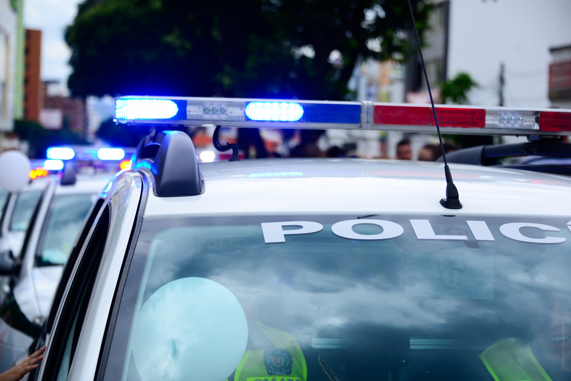 Close-up of a line of police cars with their blue lights flashing.