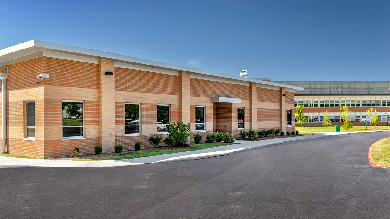 A substantial brick structure with a paved driveway, showcasing windows that meet strict storm shelter safety standards.