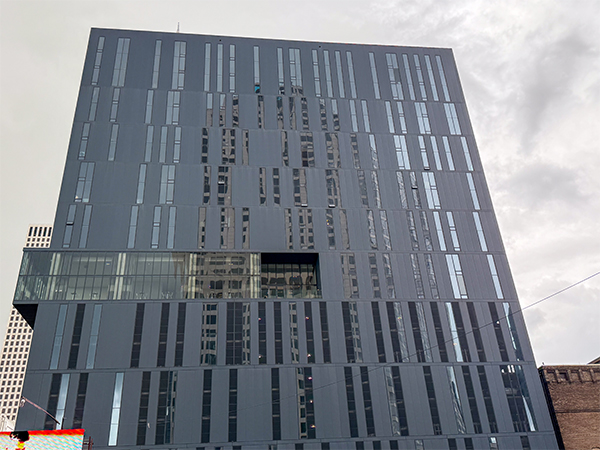 A modern building in New Orleans showcasing a random pattern of tinted windows in blue frames against gray steel panels.