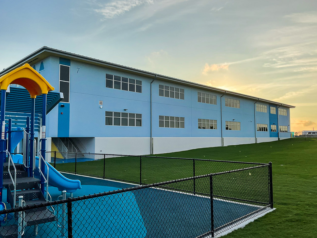 Exterior blue building with gras and slide in front