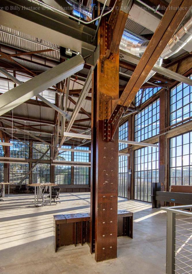 WINCO provided more than 48,000 square feet of its Series 3250 Steel Replica windows fitted with ¼” monolithic tempered clear glass. In addition to stunning aesthetics, the windows can withstand 110 mph winds as well as seismic activity. A large indoor room featuring a prominent metal beam, with natural daylight illuminating the space. The floor is visible beneath the beam, showcasing materials like steel and aluminum in the structure.