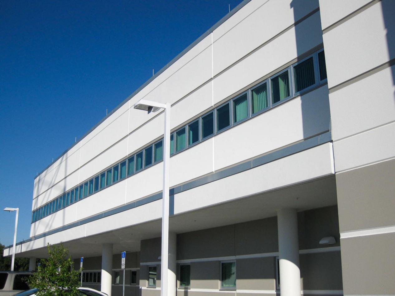 The Public Works Emergency Responders Building (PWERB) is a 2-story facility that is LEED Gold Certified and includes Winco tornado-rated windows. A tall commercial building with numerous windows against a clear blue sky. The architectural facade showcases a modern design, emphasizing the glass and structure of the property.