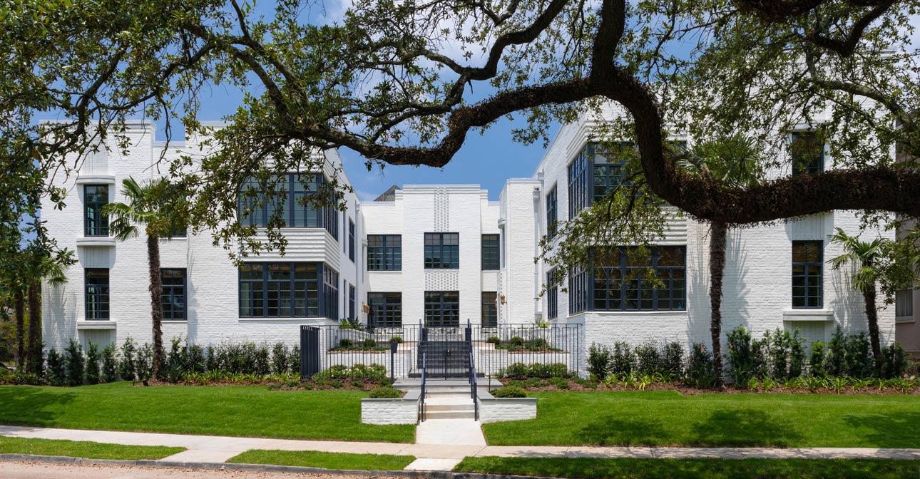 Farnsworth Apartments using Winco's Hurricane Resistant 3250 Steel Replica windows and NC-82 doors. Exterior of white brick building with large steel replica windows and trees in background