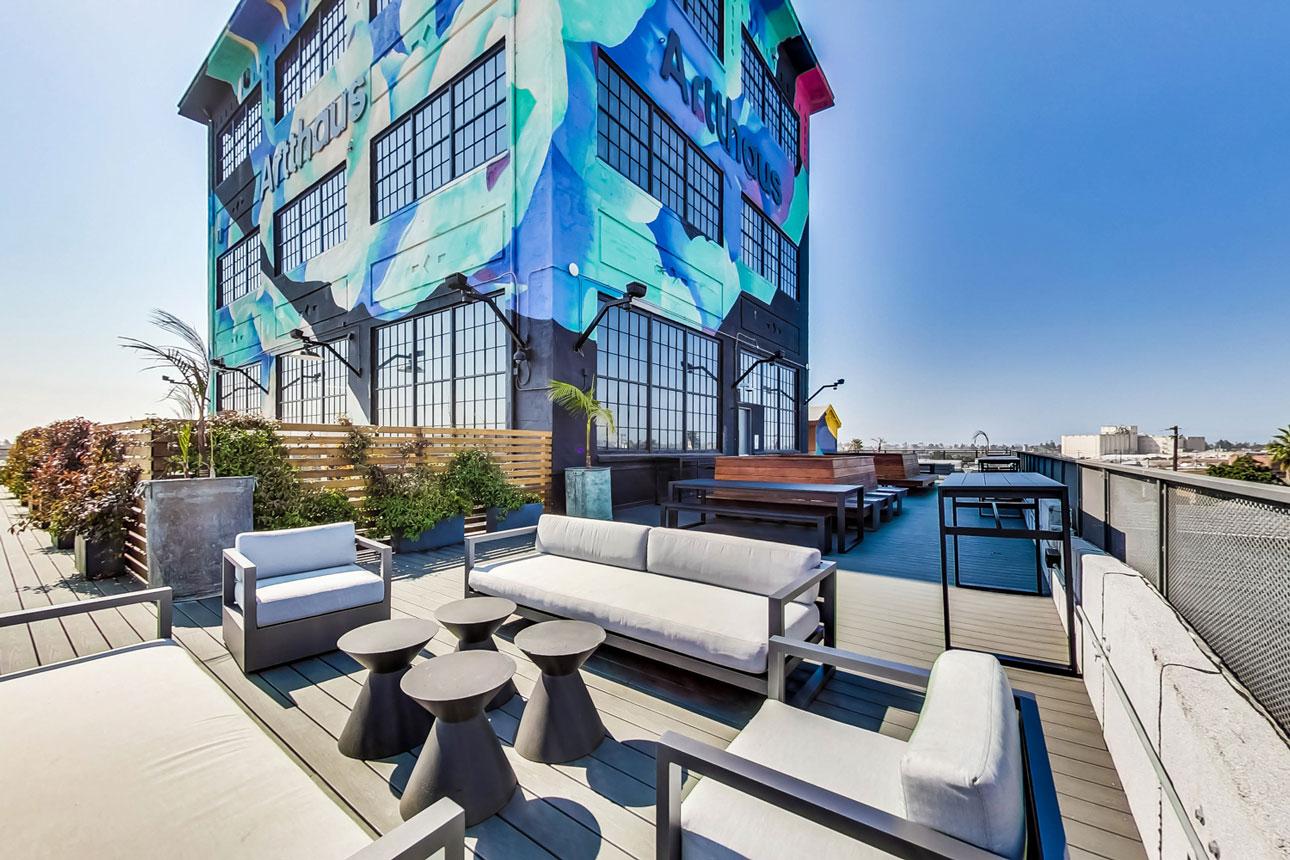 Artthaus Studios in Oakland, CA offers great views and natural light with Winco’s 3250 Steel Replica window series. Artthaus Studios_Exterior colorful brick building with large black anodized windows and patio furniture.