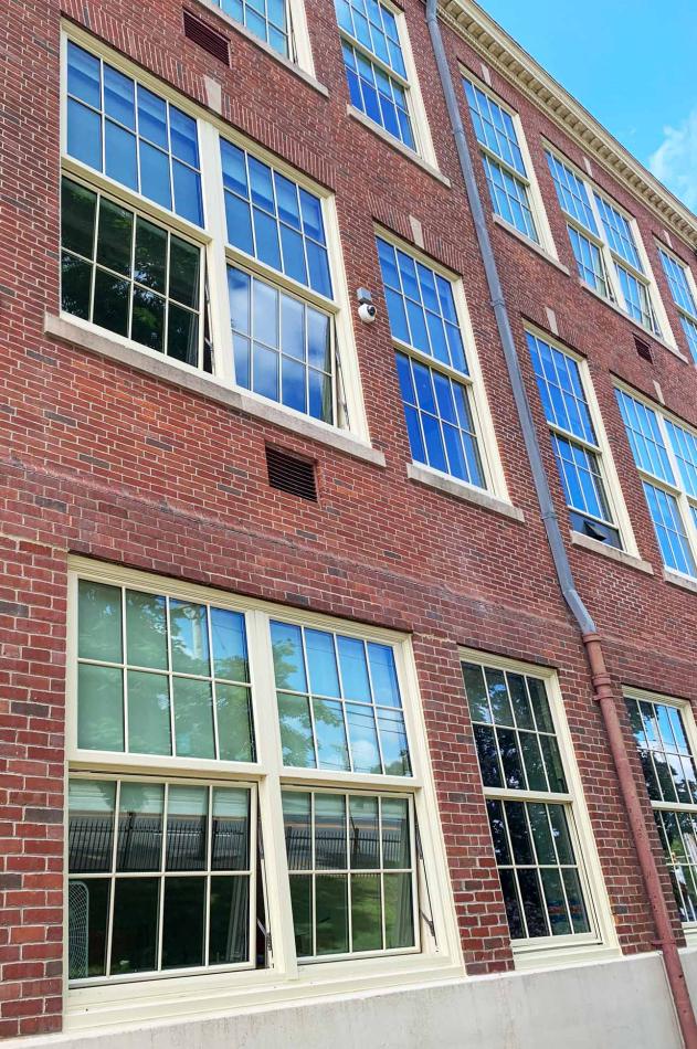 The Pawtucket School Department selected the 4410S Single Hung and 1450S Hung Replica windows for Goff Middle School. A brick building featuring a window, showcasing red brickwork and sky in background..