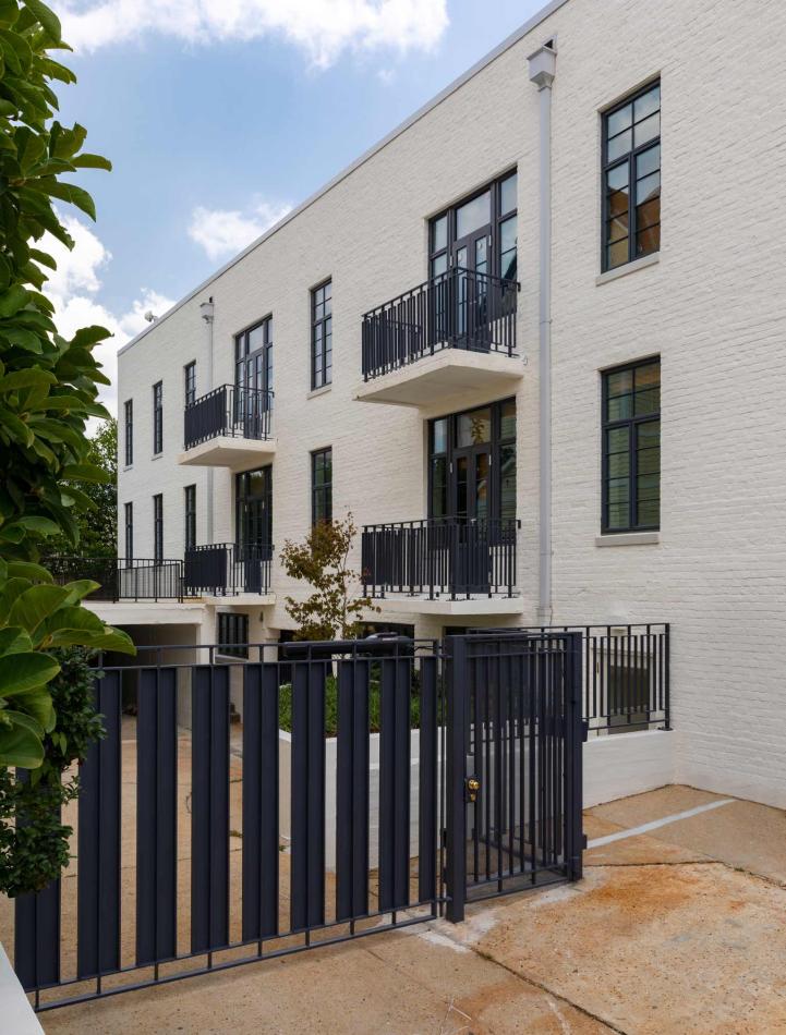 Farnsworth Apartments using Winco's Hurricane Resistant 3250 Steel Replica windows and NC-82 doors. A white brick building featuring black metal gates and balconies, showcasing WINCO’s NC82 Terrace Doors for hurricane safety