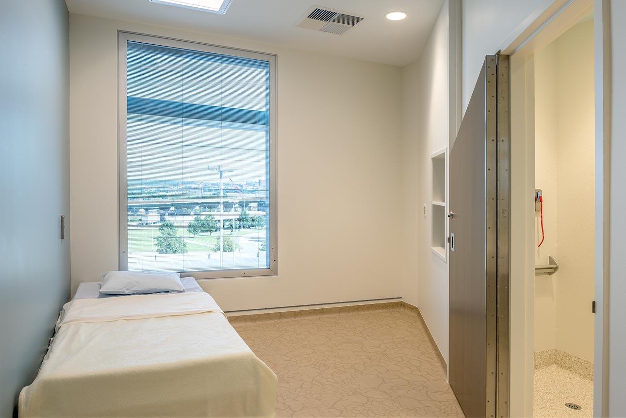 WINCO’s 8800 behavioral health window system was used in the patient rooms at Strawberry Hill Hospital to keep patients safe and allow natural light and healing views of the beautiful outdoors. A behavioral care patient room with a bed and a window, equipped with human impact resistant windows for safety.