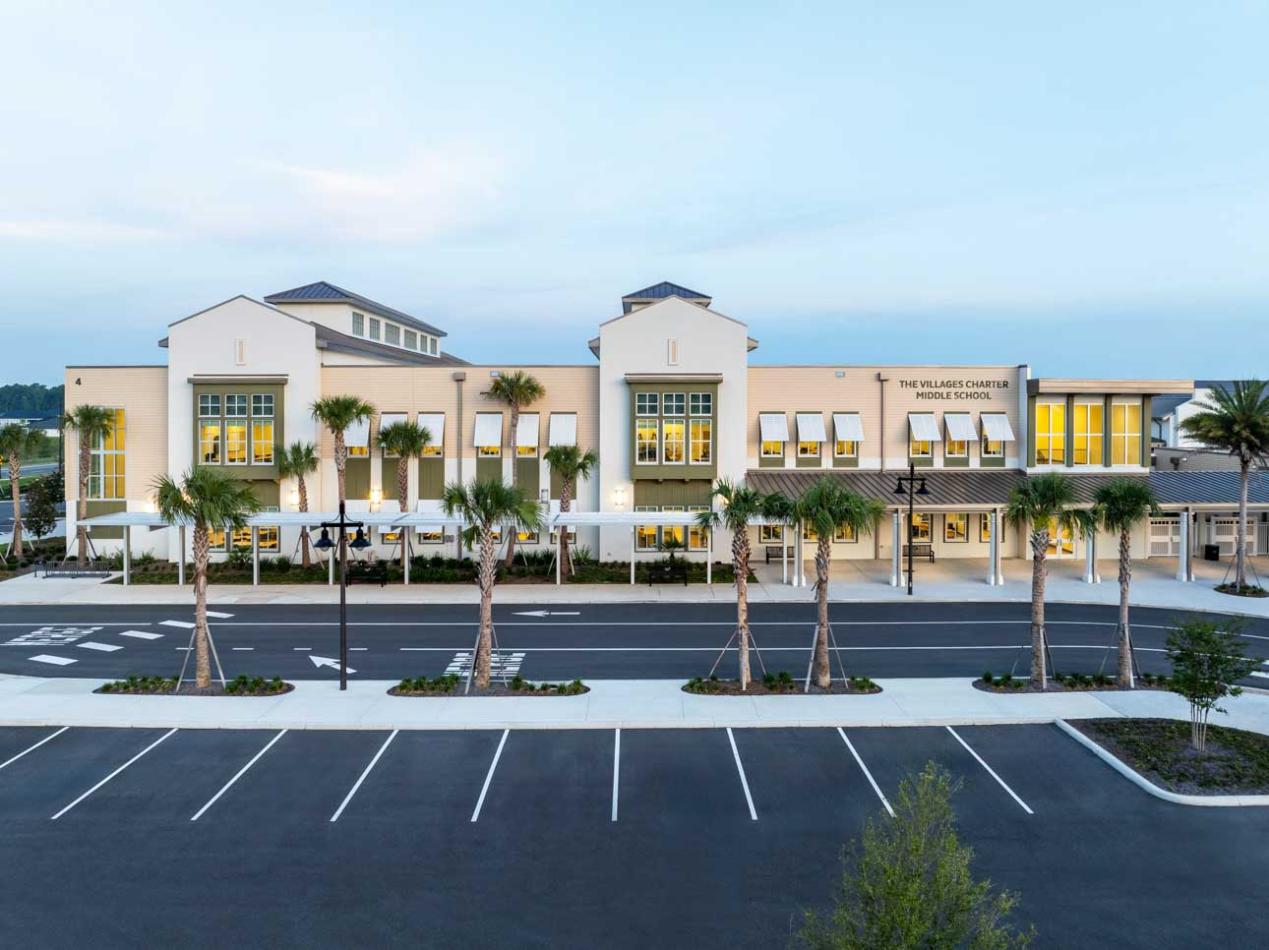 The Villages Charter K-8 School showcases Winco’s 4410 Single Hung windows, blending functionality and aesthetics. Front of school building at dusk with palm trees in front.