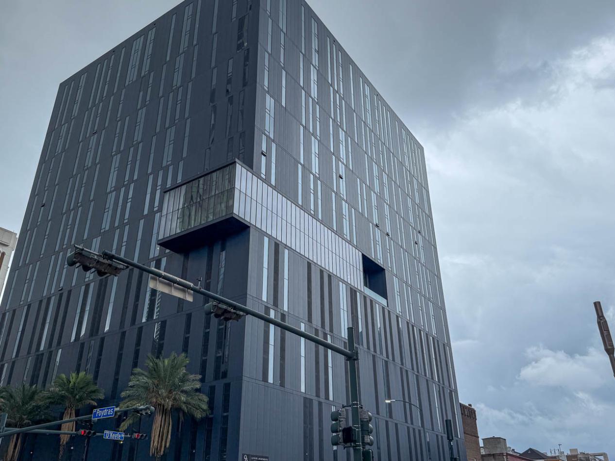 A modern building in New Orleans showcasing a random pattern of tinted windows in blue frames against gray steel panels.