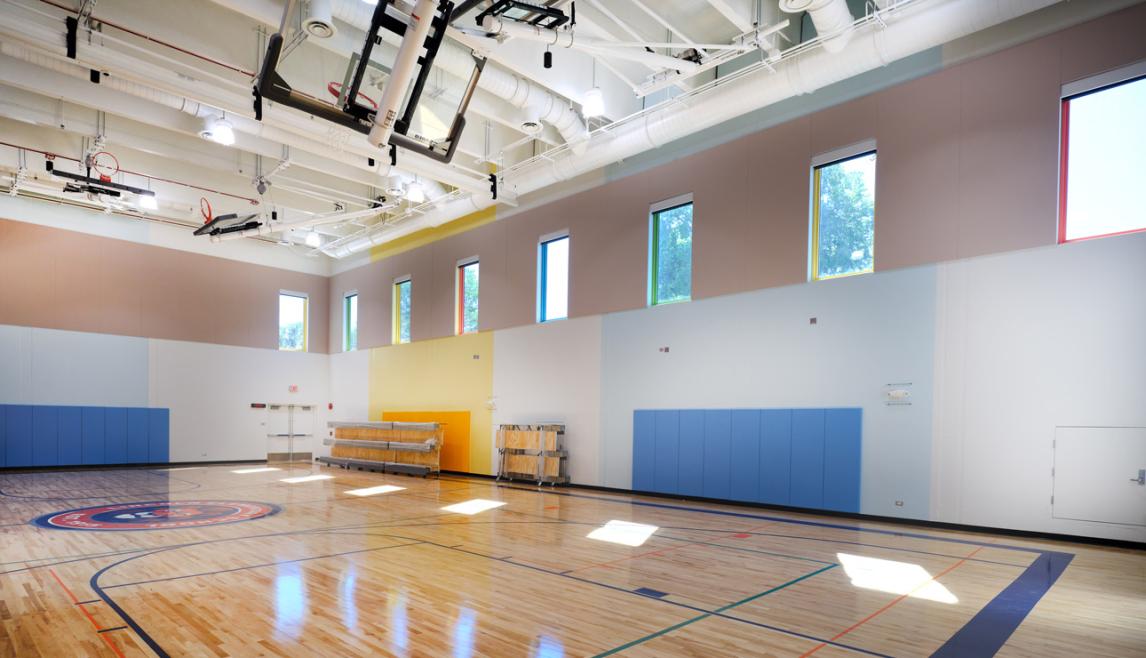 Lincoln Elementary School utilizing Winco’s FEMA 361 – ICC 500 tornado resistant windows in the gym, used as Safe Rooms for storms. A large interior gym with tornado resistant windows against a clear blue sky, showcasing a school’s safe room.