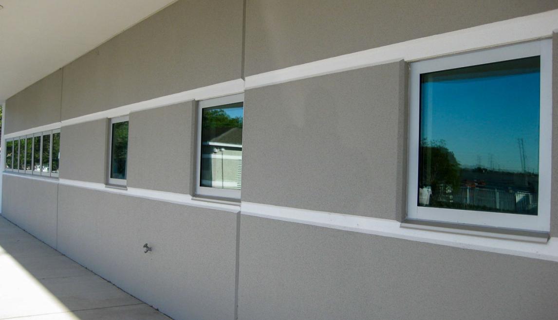 The Public Works Emergency Responders Building (PWERB) is a two-level building that holds a LEED Gold Certification and features Winco tornado-rated windows. Close-up of a window with glass, featuring a tornado resistant window. The setting includes indoor and outdoor elements, highlighting the fixture attached to the wall of a building.