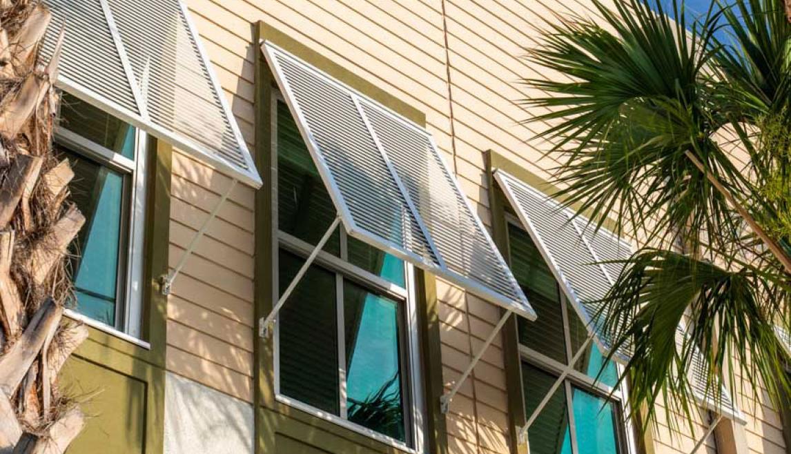 Close up of single hung windows at school building at dusk with palm trees in front.