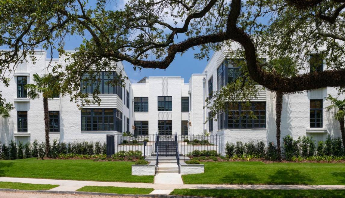 Farnsworth Apartments using Winco's Hurricane Resistant 3250 Steel Replica windows and NC-82 doors. Exterior of white brick building with large steel replica windows and trees in background