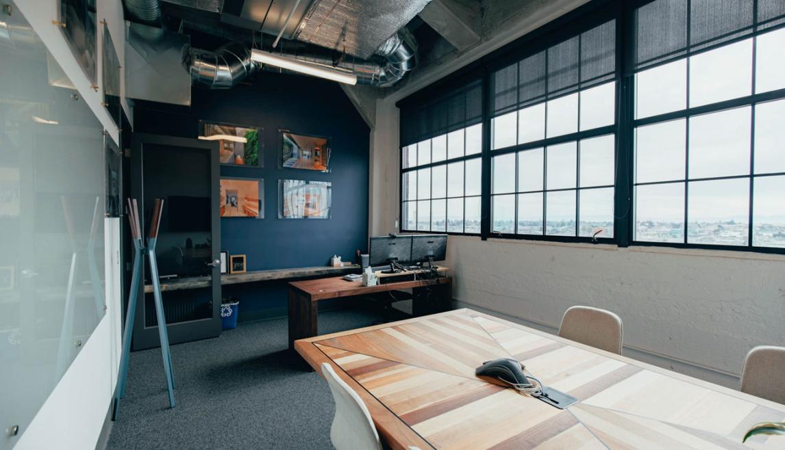Artthaus Studios in Oakland, CA offers great views and natural light with Winco’s 3250 Steel Replica window series. Interior building office room with desk and chairs and large windows.