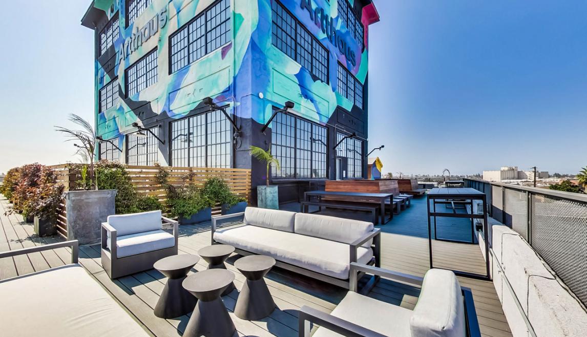 Artthaus Studios in Oakland, CA offers great views and natural light with Winco’s 3250 Steel Replica window series. Artthaus Studios_Exterior colorful brick building with large black anodized windows and patio furniture.