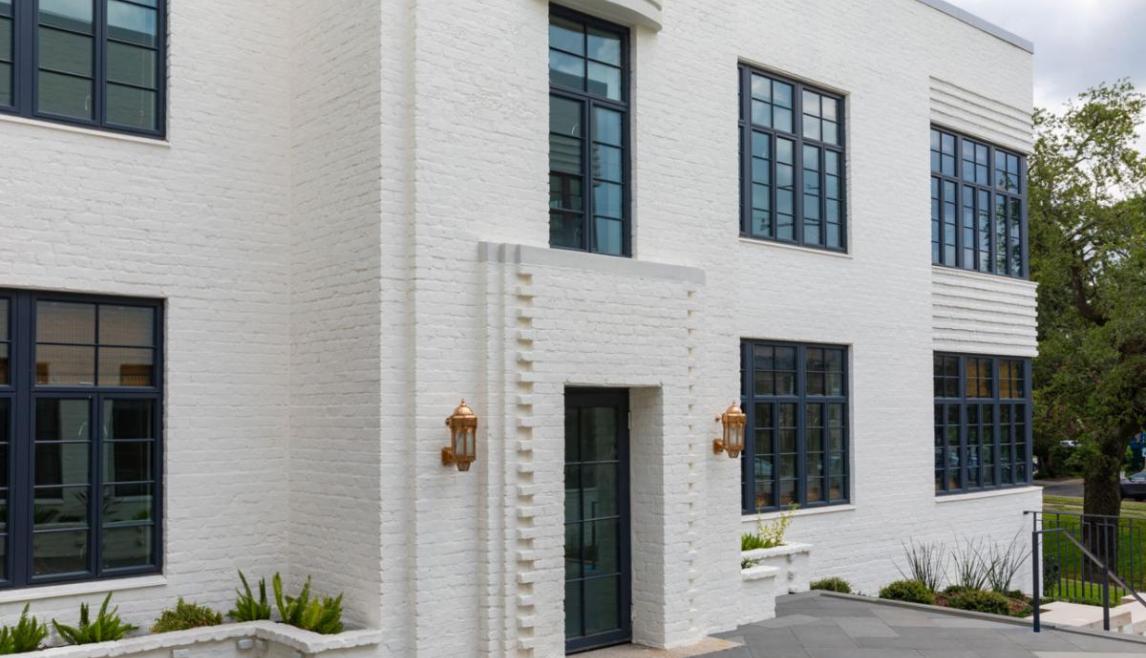 Farnsworth Apartments using Winco's Hurricane Resistant 3250 Steel Replica windows and NC-82 doors. A white building with windows and a courtyard, showcasing WINCO’s NC82 Terrace Doors that meet hurricane safety standards.