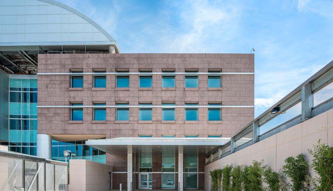 Main entrance of a hospital featuring stone architecture and Human Impact Resistant Windows for patient care rooms.