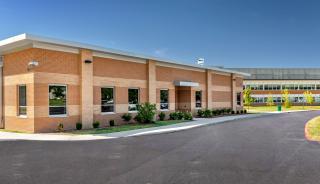 A substantial brick structure with a paved driveway, showcasing windows that meet strict storm shelter safety standards.