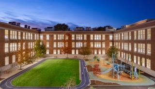 Exterior view of building at night with lights on in building shining through the windows
