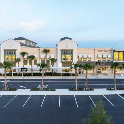 Front of school building at dusk with palm trees in front.