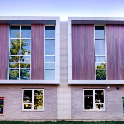 A building with a fence and a dog in front, showcasing Winco's 3325 Zero Sightline windows at Lincoln Elementary School.